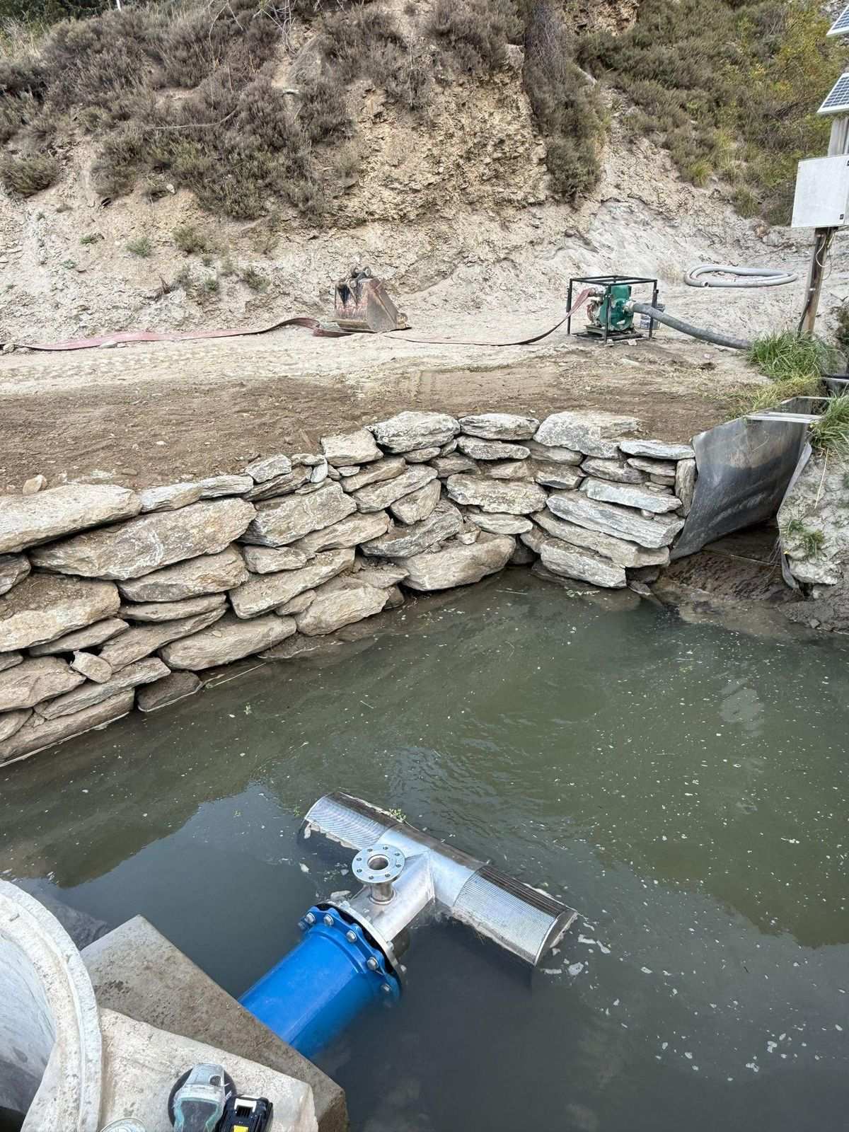 Water source intake structure with rock rip-rap and blue filter pipe