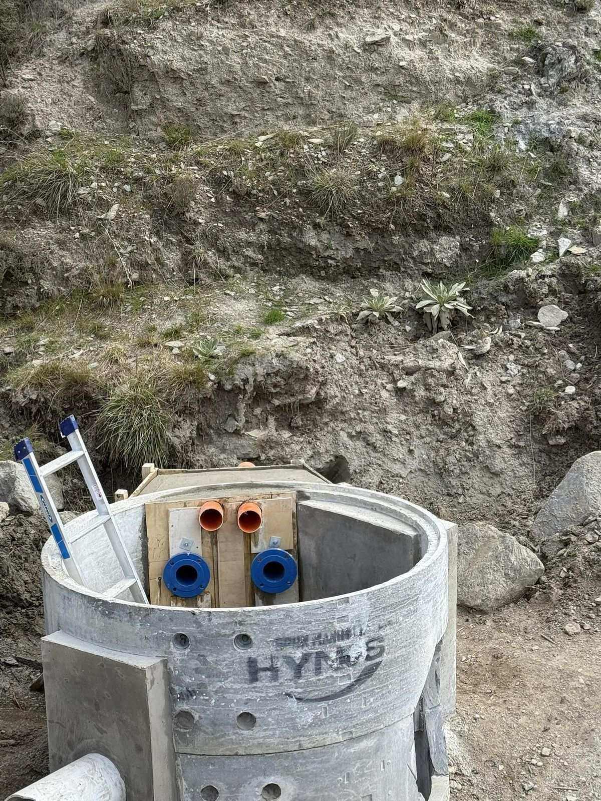 Concrete precast valve chamber with blue and orange pipe connections